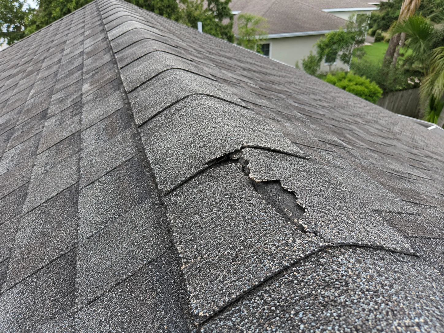 AI-generated example of a broken asphalt ridge cap with a jagged split and missing material.